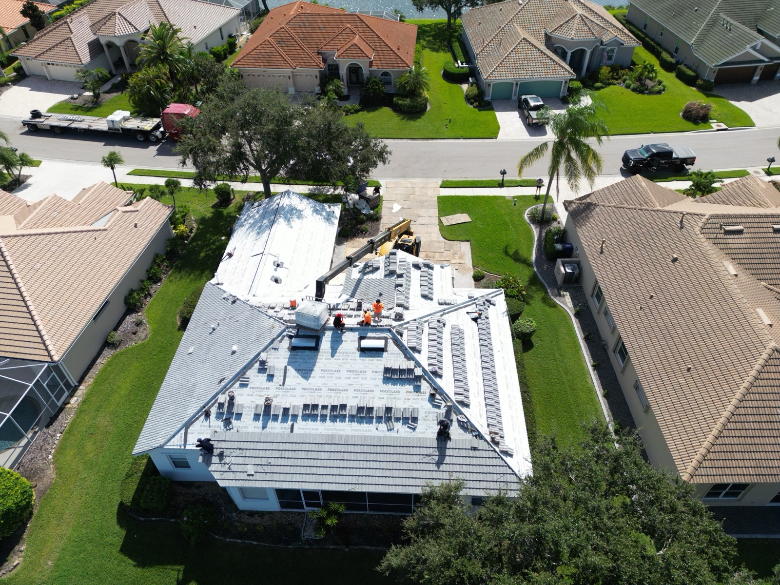 Aerial view of roofing crew installing tile with crane assistance